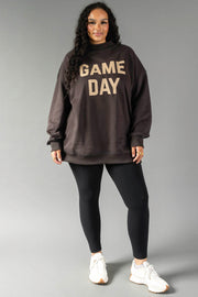 A woman stands against a gray background in the Panache Apparel Collection Dark Gray Game Day & Sunday Funday Reversible Sweatshirt, styled with black leggings and white sneakers.