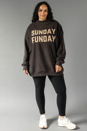 Woman wearing a Dark Gray Game Day & Sunday Funday Reversible Sweatshirt by Panache Apparel Collection, black leggings, and white sneakers, smiling against a gray background.