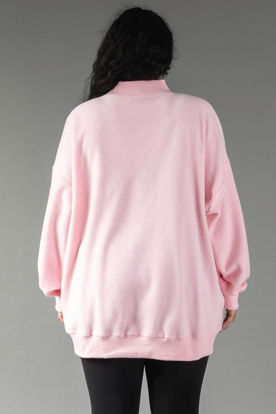 Back view of a person wearing a pink, long-sleeved, oversized Pink Merry & Cheers Reversible Sweatshirt with a mock neck.