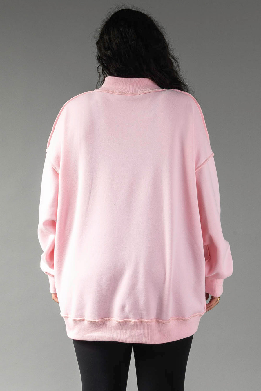 A person seen from behind wearing an oversized, long-sleeved light pink Pink Merry & Cheers Reversible Sweatshirt with a mock neckline.