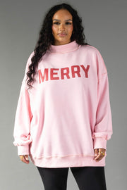 A person wears an oversized light pink Pink Merry & Cheers Reversible Sweatshirt with the word MERRY printed in red across the chest.