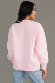 A person viewed from the back, wearing a cozy light pink Light Pink & Red Merry Sweatshirt and blue jeans.