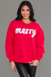 A person wearing a bright red and white Merry Sweatshirt with the word merry in white textured lettering on a fuzzy fabric.