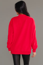 A person seen from behind wears a red Red Nice & Naughty Reversible Sweatshirt with a mock neck and black pants, styled as a cozy holiday outfit.