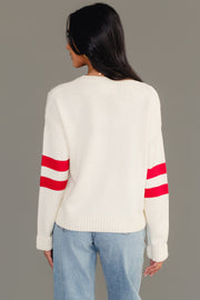 A person is shown from the back, standing against a plain gray background, wearing the Cream & Red 13 Sweater by Panache Apparel Collection paired with light blue jeans. The sweater is cream-colored and features two red stripes on each sleeve.