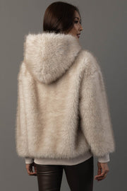 A woman with long brown hair, seen from behind, models the Panache Apparel Collection’s Cream Faux Fur Hooded Sweatshirt paired with black leather pants against a plain gray background.