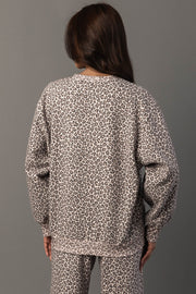 A person with long brown hair is seen from behind against a plain gray background, wearing the Panache Apparel Collection Cream & Brown Leopard Sweatshirt.