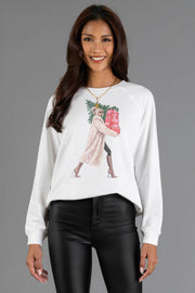 White crewneck Girl Carrying Presents & Tree Sweatshirt by Panache Apparel Collection featuring a graphic of a woman in a long coat carrying a Christmas tree and a stack of gifts.