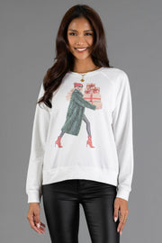 Panache Apparel Collection Girl Carrying Christmas Presents Sweatshirt, a white long-sleeved top featuring a woman in a green coat and red boots carrying a stack of holiday presents.