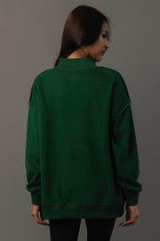 A person with long dark hair, wearing the Panache Apparel Collection Green Game Day & Sunday Funday Reversible Sweatshirt and black pants, stands facing away from the camera against a plain gray background.