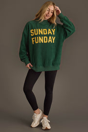 A woman smiles as she stands against a plain brown background, wearing the Panache Apparel Collection’s Green Game Day & Sunday Funday Reversible Sweatshirt, which features bold yellow SUNDAY FUNDAY lettering. She pairs the cozy oversized sweatshirt with black leggings and white sneakers, touching her hair for a relaxed weekend look that’s perfect for lounging or cheering on your favorite team.