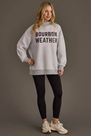 A woman is wearing a Light Gray Whiskey Weather & Bourbon Weather Reversible Sweatshirt from Panache Apparel Collection, paired with black leggings and white sneakers, standing against a plain background and smiling.