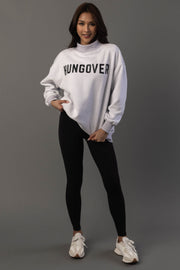 A woman stands and smiles, wearing the Panache Apparel Collection Light Gray Day Drinking & Hungover Reversible Sweatshirt, paired with black leggings and white sneakers, posing against a gray background.