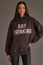A woman stands with her hand on her hip, wearing the Panache Apparel Collection’s Dark Gray Day Drinking & Hungover Reversible Sweatshirt, featuring bold “DAY DRINKING” lettering on the front.