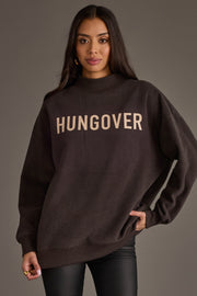 A woman stands wearing the Panache Apparel Collection’s Dark Gray Day Drinking & Hungover Reversible Sweatshirt, paired with black pants, against a plain gray background.