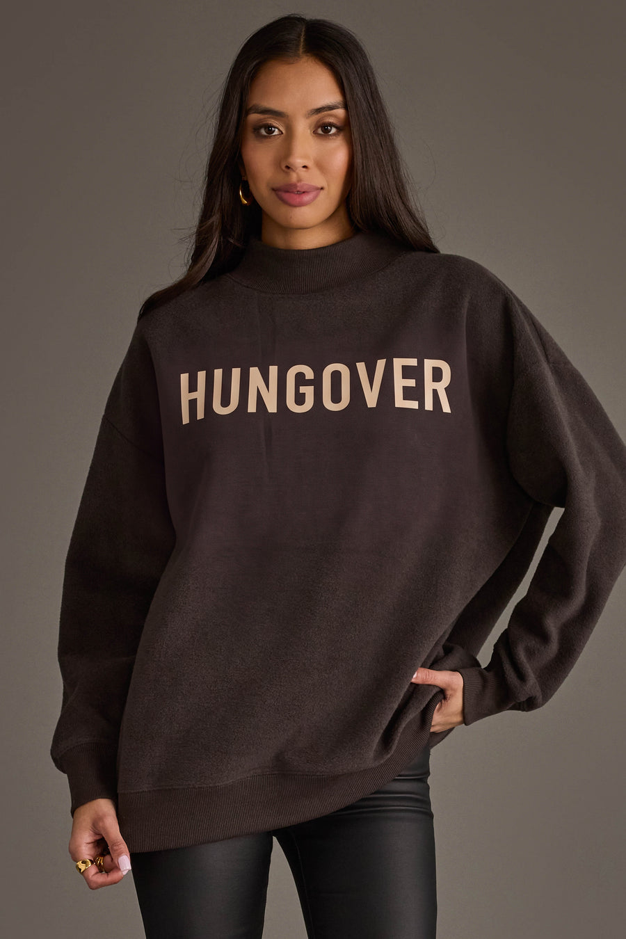 A woman stands wearing the Panache Apparel Collection’s Dark Gray Day Drinking & Hungover Reversible Sweatshirt, paired with black pants, against a plain gray background.
