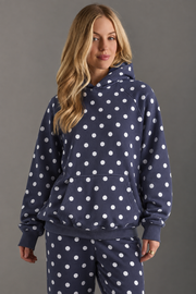 A person models the Panache Apparel Collection Navy & White Polka Dot Hooded Sweatshirt with coordinating navy pants, standing against a gray background and looking at the camera with a slight smile.