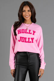 A comfortable Pink Holly Jolly Sweatshirt in pink with HOLLY JOLLY in textured dark pink varsity lettering on the chest.