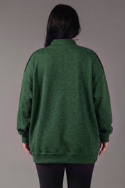 A person with long dark hair, shown from the back, wears a loose-fitting Panache Apparel Collection Green Game Day & Sunday Funday Reversible Sweatshirt and black leggings, standing against a plain gray background.