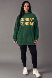A person stands against a gray background wearing the Green Game Day & Sunday Funday Reversible Sweatshirt by Panache Apparel Collection, paired with black leggings and white sneakers.