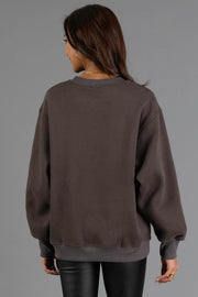 A woman with long brown hair is seen from behind, wearing the Panache Apparel Collection Charcoal & Mint Midwest Sweatshirt and black pants, standing against a plain gray background.