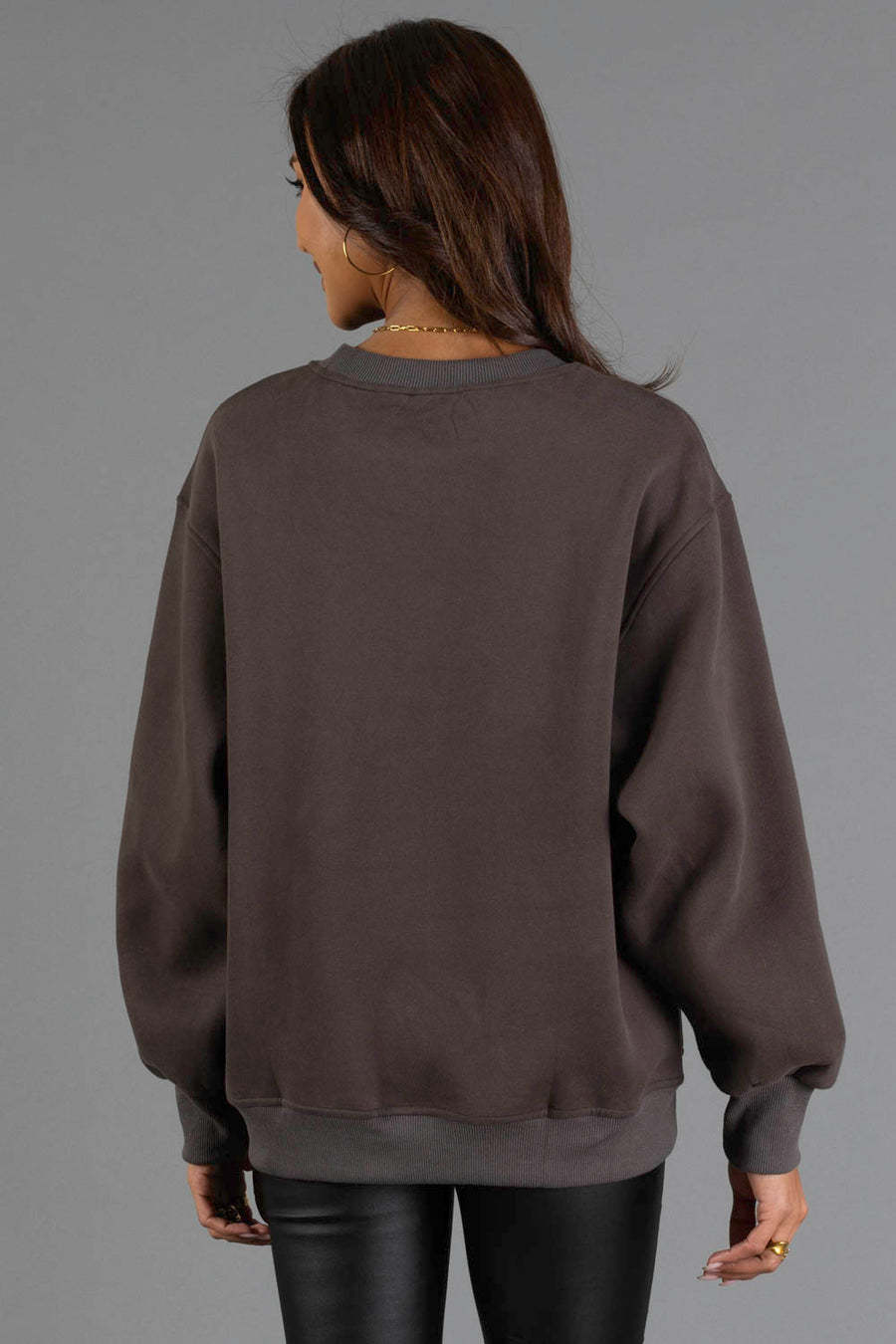 A woman with long brown hair is seen from behind, wearing the Panache Apparel Collection Charcoal & Mint Midwest Sweatshirt and black pants, standing against a plain gray background.