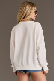 A woman with long blonde hair, wearing sunglasses, the Howdy Honey Sweatshirt by Panache Apparel Collection, and denim shorts stands facing away from the camera against a plain background.