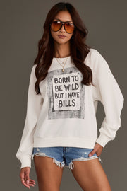 A woman wearing sunglasses and denim shorts stands against a plain background with one hand in her pocket, styling the Panache Apparel Collection “Born to Be Wild Sweatshirt,” featuring the playful slogan “BORN TO BE WILD BUT I HAVE BILLS” printed on the front.