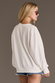 A woman wearing sunglasses and the Panache Apparel Collection Fringe Cowgirl Sweatshirt with denim shorts stands facing away, offering a side and back view against a plain background.