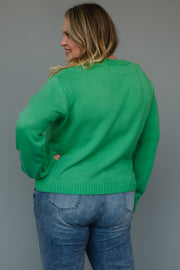 A person wearing a relaxed fit, bright mint green Mint Merry Sweater and blue jeans.