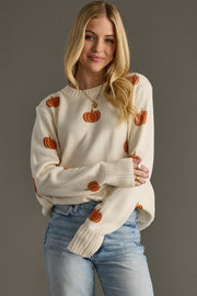 Woman wearing Panache Apparel’s ivory pumpkin print sweater with orange knit details and ribbed cuffs.