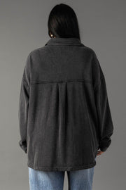 A person with long dark hair stands with their back to the camera, wearing Panache Apparel Collection's Black Washed Soft Button Up and light blue jeans against a plain gray background.