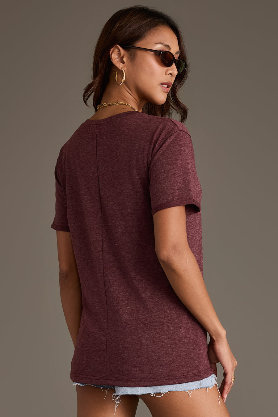 A woman wearing a relaxed fit Burgundy Wine Tee in burgundy with a center back seam and denim shorts from Panache Apparel Collection.