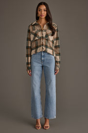 A woman stands facing forward against a plain background, wearing the Panache Apparel Collection Tan, Dark Green & Rust Plaid Button Up, paired with light blue high-waisted jeans and open-toe heels; her long hair is styled down.