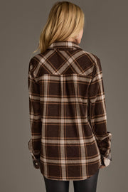 A person with long blonde hair is shown from the back, wearing the Panache Apparel Collection’s Dark Brown, Cream & Black Plaid Button Up with rolled sleeves and black pants against a plain background.
