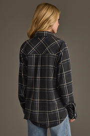 Wearing the Panache Apparel Collection’s Dark Gray, Light Blue & White Plaid Button Up, a person with long blonde hair and light blue jeans stands with their back to the camera against a plain background.
