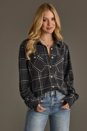 A woman with long blonde hair stands against a plain background, smiling with her hands in her pockets while wearing the Panache Apparel Collection Dark Gray, Light Blue & White Plaid Button Up and blue jeans.