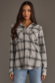 A woman with long dark hair wears the Panache Apparel Collection Light Gray, Black & Sage Plaid Button Up and light blue jeans, standing against a plain gray background.