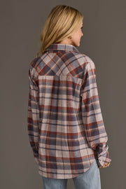A person with long blonde hair, dressed in the Panache Apparel Collection Dusty Blue, Brick & Tan Plaid Button Up and light blue jeans, is facing away from the camera against a plain gray background.