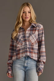 A woman with long blonde hair wears the Panache Apparel Collection’s “Dusty Blue, Brick & Tan Plaid Button Up,” paired with light blue jeans, standing against a plain gray background.