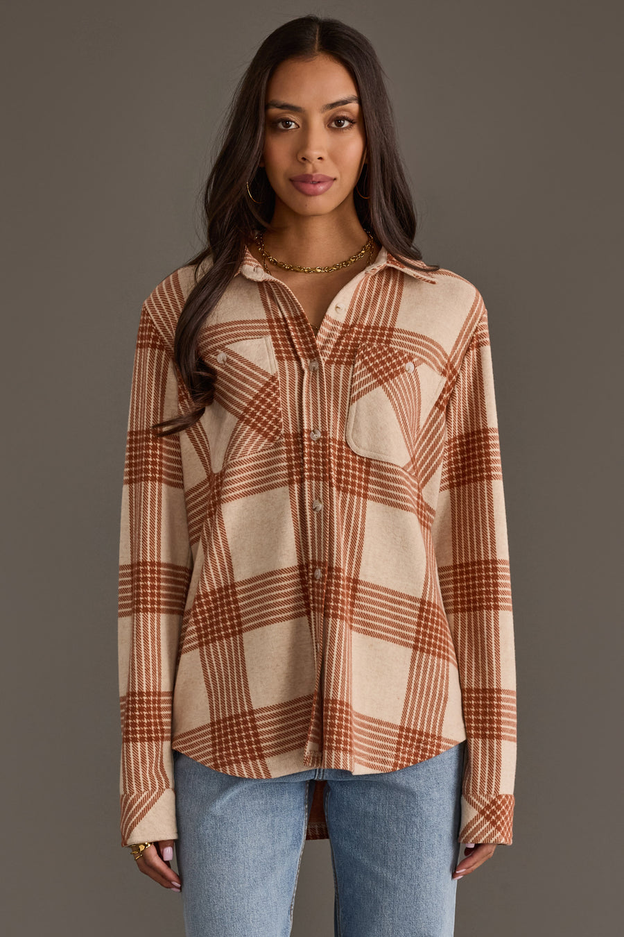 A woman wearing the Panache Apparel Collection Cream & Rust Plaid Button Up with blue jeans stands facing forward against a plain grey background.
