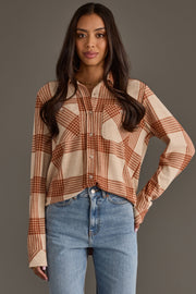 A woman with long brown hair models the Panache Apparel Collection Cream & Rust Plaid Button Up, paired with blue jeans, standing against a plain gray background.