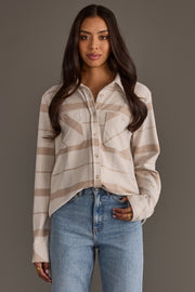 A woman with long dark hair wears the Panache Apparel Collection Cream, Tan & Gray Plaid Button Up, paired with blue jeans, standing against a plain gray background.
