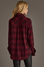 A woman with blonde hair wearing the Panache Apparel Collection Maroon & Black Plaid Button Up and black pants stands facing away against a plain gray background.