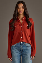 A woman with long brown hair is wearing the Panache Apparel Collection’s Dark Rust Super Soft Button Up, styled with blue jeans and standing against a plain brown background.