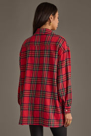 A person with long dark hair, wearing gold hoop earrings, is shown from behind wearing the Panache Apparel Collection Red Multicolored Boyfriend Flannel Button Up and black pants against a plain gray background.