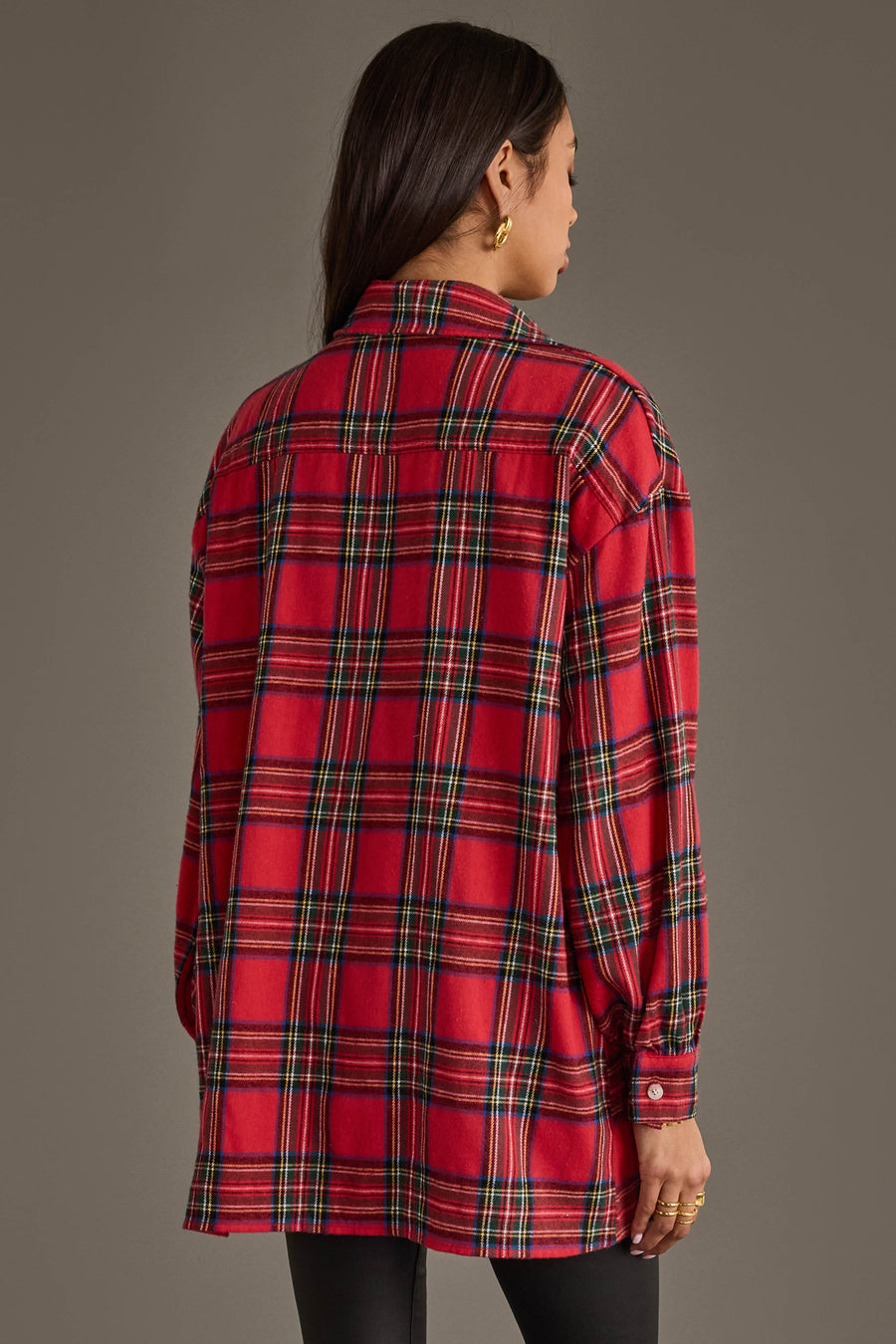 A person with long dark hair, wearing gold hoop earrings, is shown from behind wearing the Panache Apparel Collection Red Multicolored Boyfriend Flannel Button Up and black pants against a plain gray background.