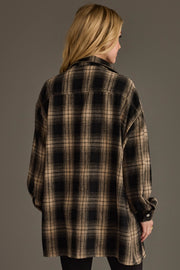 A person with long blonde hair is seen from behind, wearing the Panache Apparel Collection’s Black & Tan Boyfriend Fit Plaid Button Up, standing against a plain gray background.