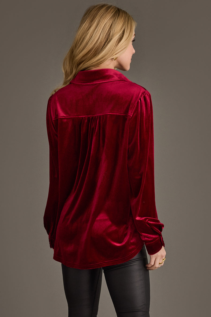 A woman with long blonde hair models the Panache Apparel Collection Burgundy Velvet Button Up and black pants, standing with her back to the camera against a plain background.