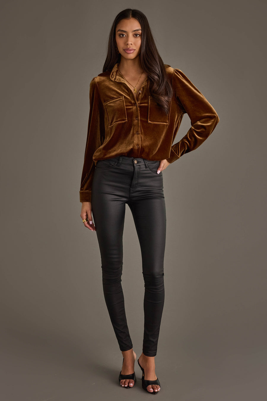 Woman with long dark hair and a neutral expression stands against a plain background, wearing the Panache Apparel Collection Bronze Velvet Button Up, black fitted pants, and black open-toe heels.
